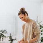 Smiling woman wraps Christmas gifts at home, creating a warm festive atmosphere.